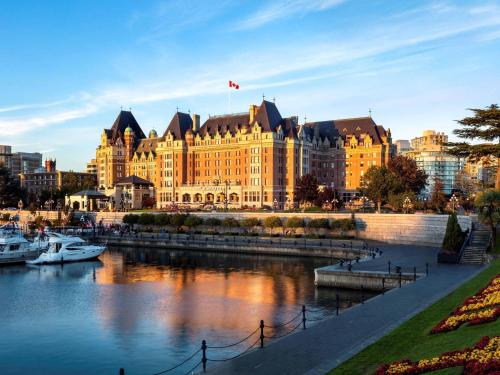 a large building next to a river with boats in it at Fairmont Empress Hotel in Victoria
