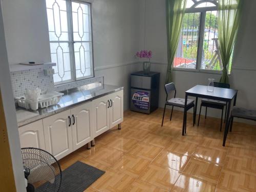 a kitchen with white cabinets and a table and chairs at fully appartement in Quitangil