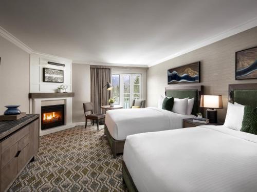 a hotel room with two beds and a fireplace at Fairmont Chateau Whistler in Whistler