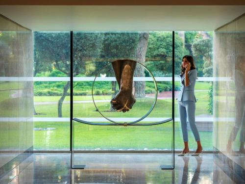a woman talking on a cell phone in front of a sculpture at Swissotel Buyuk Efes Izmir in Izmir