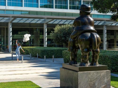 a woman standing next to a statue in front of a building at Swissotel Buyuk Efes Izmir in Izmir