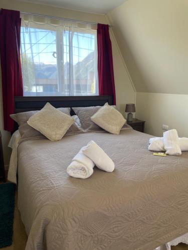 a bedroom with two towels on a bed with a window at CabañasRioBlanco in Chaitén