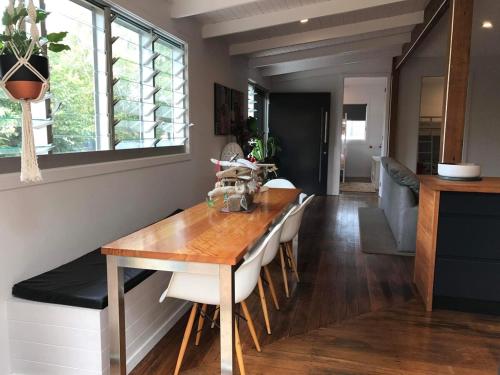 a dining room with a wooden table and white chairs at Coastal 4 bedroom Sawtell home with Pool in Sawtell
