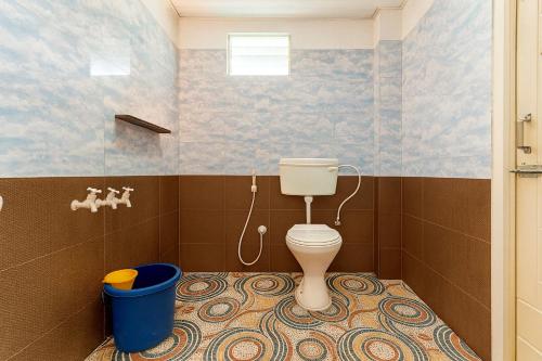 a bathroom with a toilet and a blue bucket at Rainy Cloud Homestay 3B, Balcony, Home Food in Chikmagalūr