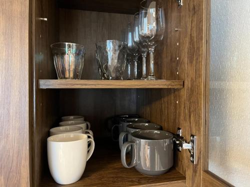 a cupboard with a row of cups and bowls at 江の島ハウス in Fujisawa
