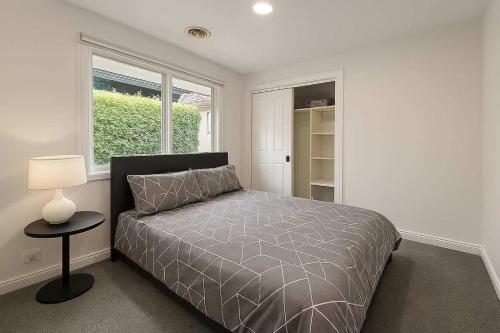 a bedroom with a bed and a lamp and a window at Entire House in Berwick close to Parks & Schools in Beaconsfield