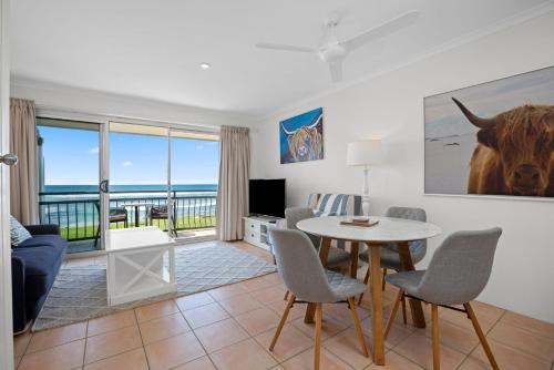 ein Wohnzimmer mit einer Couch und einem Tisch mit Stühlen in der Unterkunft Apartment 9T in Lennox Head