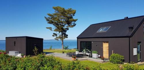 una casa negra con el océano en el fondo en Villa With Lake View Over Vättern In Vadstena, en Vadstena