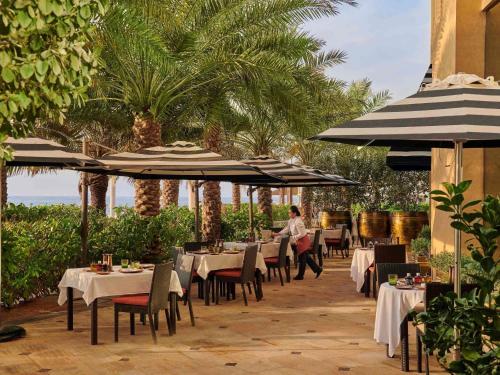 a restaurant with tables and umbrellas on a patio at Fairmont Ajman in Ajman 