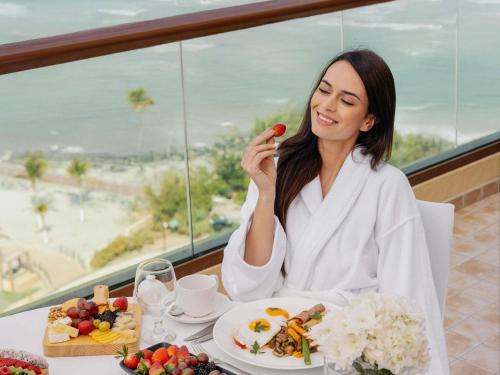 a woman sitting at a table with a plate of food at Fairmont Ajman in Ajman 