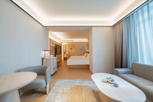 a hotel room with a bed and a living room at JI Hotel Qingdao Haier Industrial Park Wannianquan Road Subway Station in Qingdao