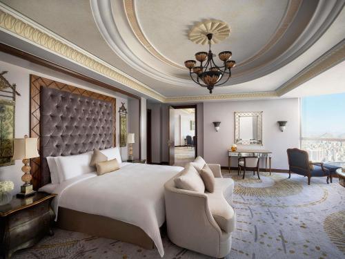 a bedroom with a large white bed and a chair at Raffles Makkah Palace in Makkah