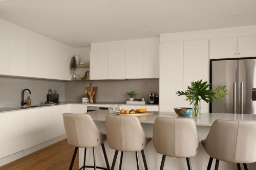 Sophisticated Beach Abode في بيرجيان بيتش: مطبخ مع دواليب بيضاء وطاولة مع كراسي