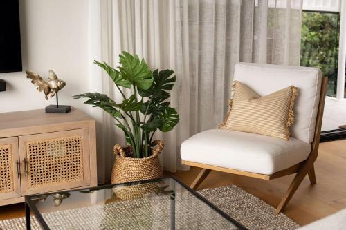 Sophisticated Beach Abode في بيرجيان بيتش: غرفة معيشة فيها كرسي وزرع