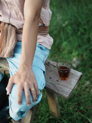 a person sitting on a bench with a cup of tea at Nongtao Homestay in Ban Dong Than