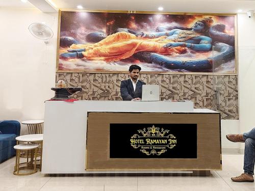 un hombre de pie en una recepción con un portátil en Hotel Ramayan Inn, en Rishīkesh