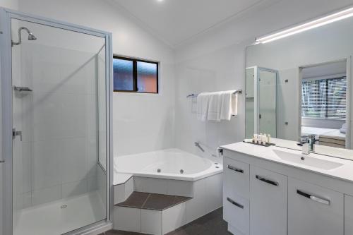 a white bathroom with a shower and a sink at Ingenia Holidays Cairns Coconut in Cairns