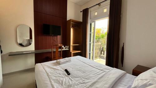 a bedroom with a white bed and a window at Hause of Bejo Yogyakarta in Demangan