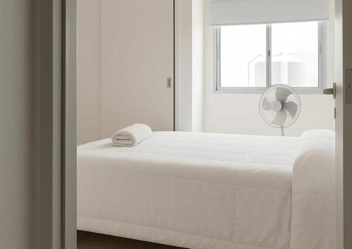 a white bed in a white room with a window at Dpto GAMA a cuadras del corsodromo in Gualeguay