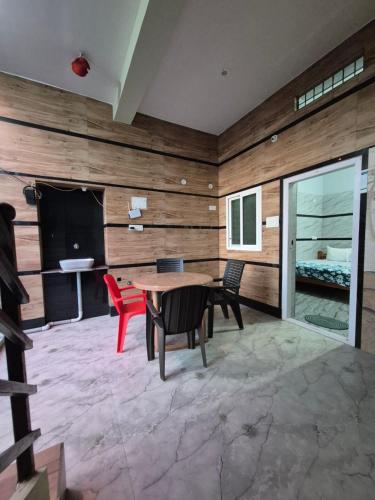 Zimmer mit einer Holzwand mit einem Tisch und Stühlen in der Unterkunft Khushi's Paradise Villa hampi in Hampi