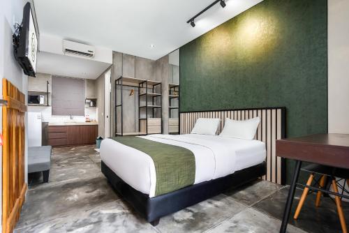 a bedroom with a bed and a desk and a kitchen at Garden View by Calli Rooms in Jember