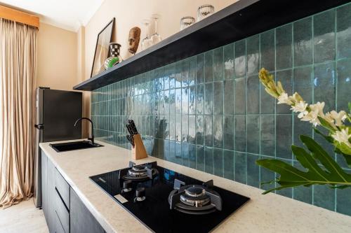 eine Küche mit einem Herd und einer grünen Kachelwand in der Unterkunft Tranquil Oasis Pool, Seamless WiFi and Workspace in Bingin Beach