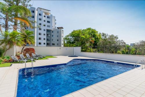 a swimming pool with chairs next to a building at Burgess @ Kings Beach Apartments in Caloundra