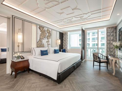 a hotel room with a large bed and a desk at Mövenpick Myth Hotel Patong Phuket in Patong Beach