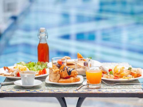 ein Tisch mit Tellern voller Essen und Getränke in der Unterkunft Mövenpick Myth Hotel Patong Phuket in Patong Beach