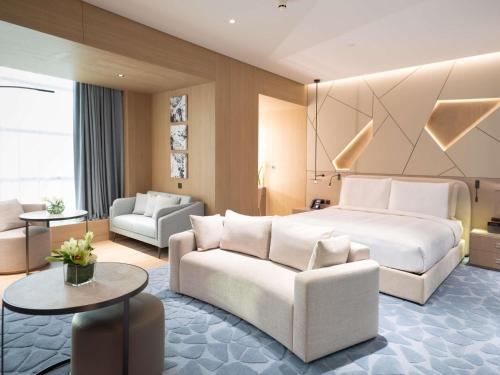 a hotel room with a large bed and a couch at La Cigale Hotel Managed by Accor in Doha