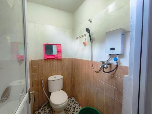 Un baño con inodoro y un televisor en la pared. en Loox Hotel Grand Aroya, en Mataram