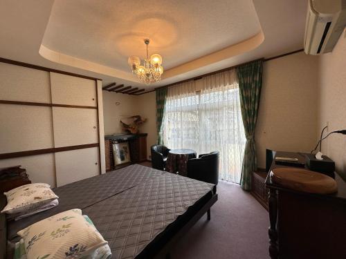 a bedroom with a bed and a chandelier and a window at LiveCafe & Hotelひすいの海 in Itoigawa