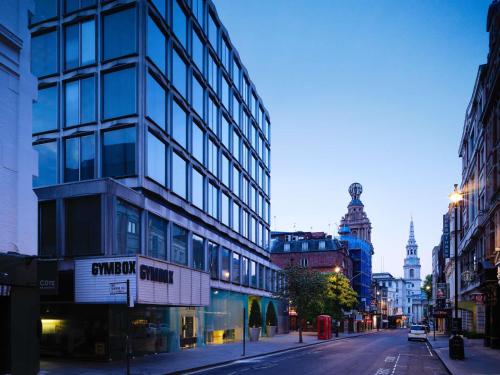 a city street with a tall glass building at St Martins Lane London in London