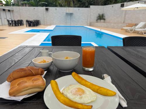 a table with a breakfast of eggs and bread next to a pool at Los Bosques INN in San Ramón