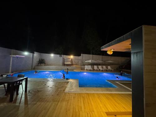 a swimming pool at night with people in it at Los Bosques INN in San Ramón