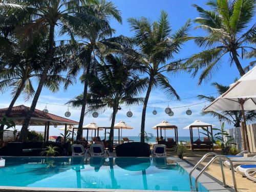 una piscina con palmeras al fondo en Nico Beach Hotel, en Hikkaduwa
