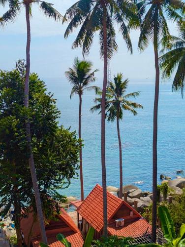 a view of the ocean from a resort with palm trees at Ecohouse Hòn Sơn in Lai Sơn