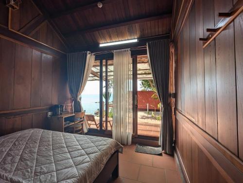 a bedroom with a bed and a view of the ocean at Ecohouse Hòn Sơn in Lai Sơn