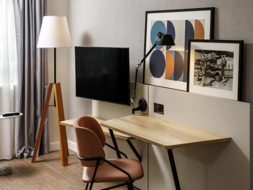 a room with a desk with a television and a chair at Aparthotel Adagio London Sutton Point in Sutton
