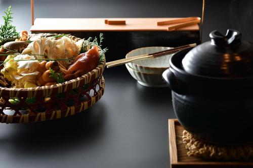 a basket of food on a table next to a pot at Shima Onsen Yoshimoto in Nakanojo