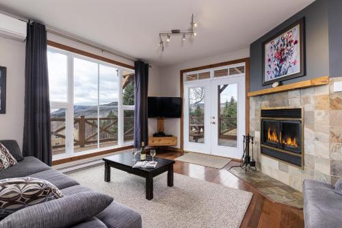 a living room with a couch and a fireplace at Condo 120B, Hot Tub, Panoramic Views & Game Area in Petite-Rivière-Saint-François