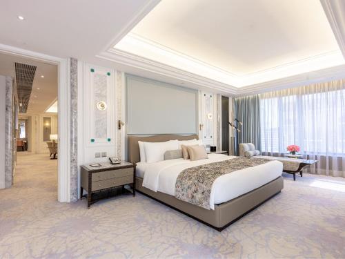 a bedroom with a large bed and a living room at Grand Emperor Hotel in Macau