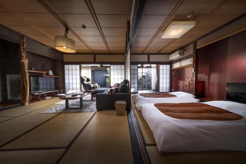 a hotel room with three beds and a living room at Kurotake in Achi