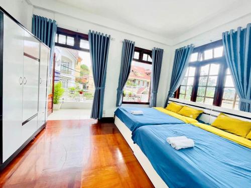 a bedroom with blue curtains and a large bed at Dona Hotel in Da Lat