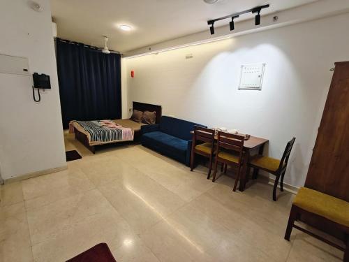 a living room with a blue couch and a table at Cozy studio with Dolby Sounds Hiranandani Estate in Kolshet