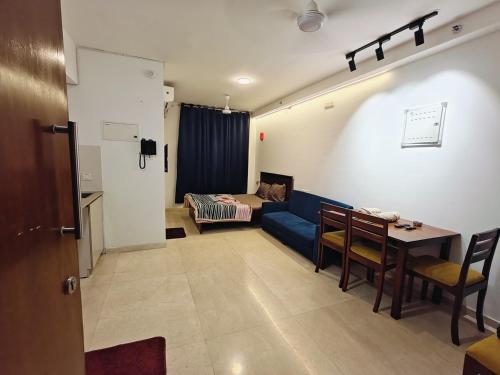 a living room with a blue couch and a table at Cozy studio with Dolby Sounds Hiranandani Estate in Kolshet