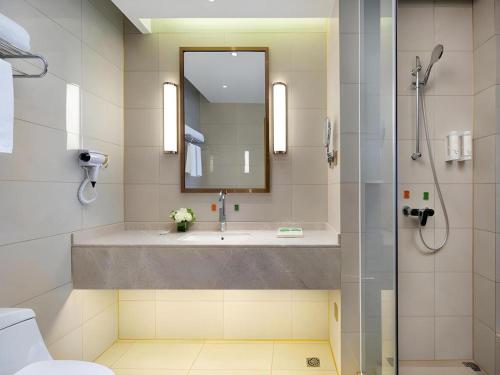 a bathroom with a sink and a shower with a mirror at Vienna Hotel Hunan Changsha Gaoling in Changsha