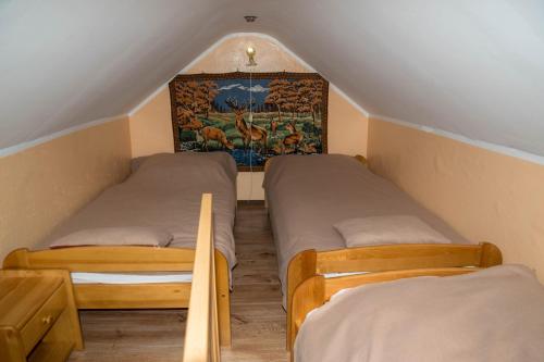 ラトクフにあるDomek HANAのベッド2台が備わる屋根裏部屋で、壁に絵画が飾られています。