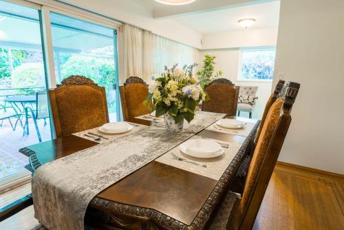 a dining room table with a vase of flowers on it at South Vancouver Garden Home in Vancouver