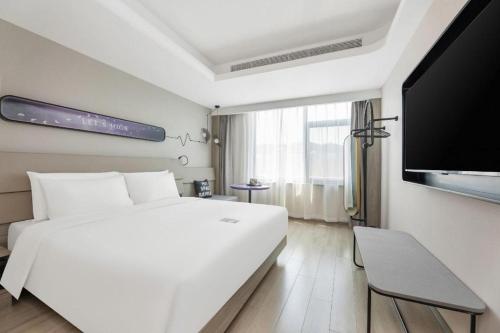 Un dormitorio blanco con una cama grande y un televisor de pantalla plana. en Atour X Hotel Jinan Jingshi Road Provincial Sports Center, en Jinan